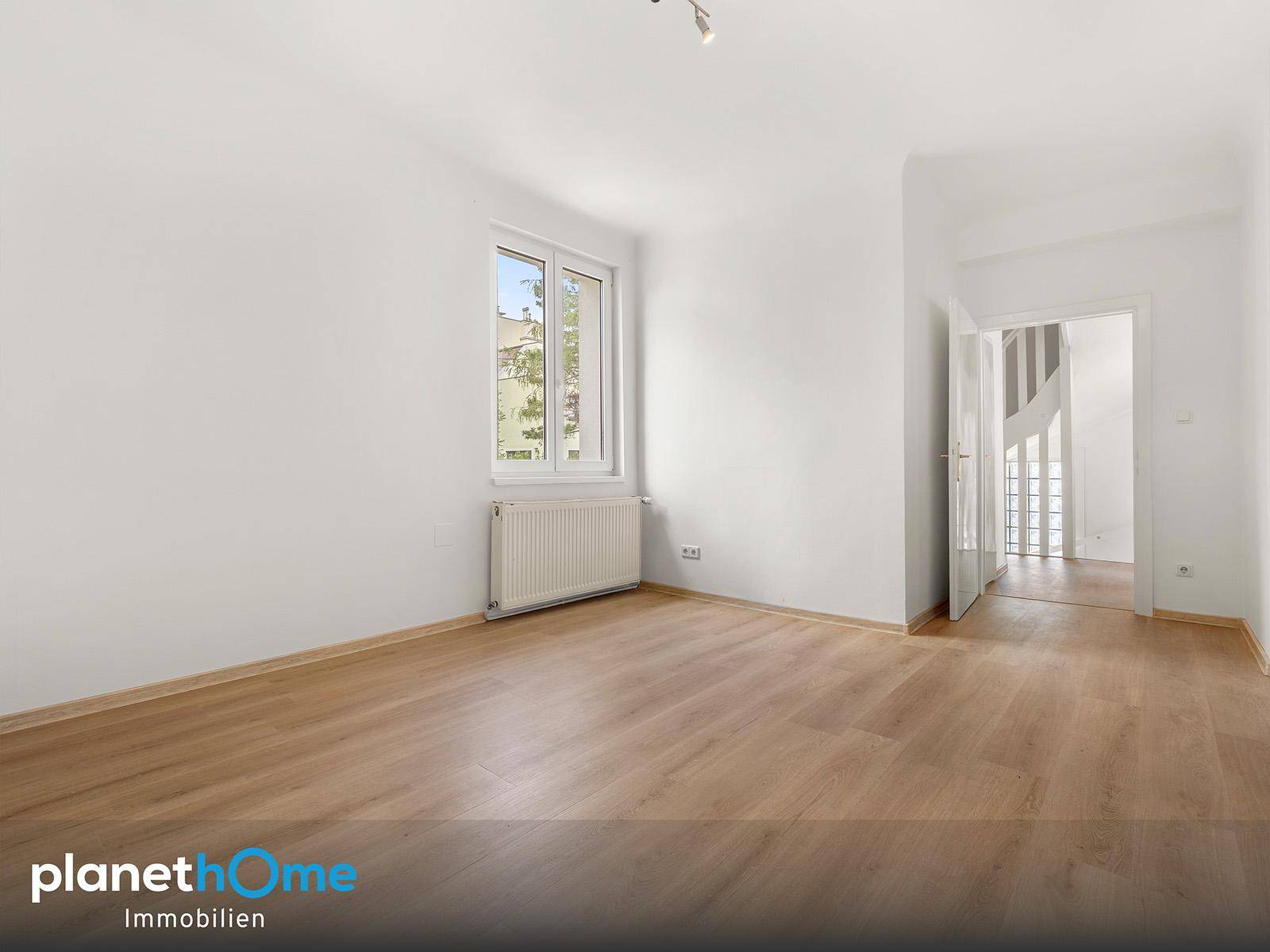 Helles Zimmer mit Laminatboden und Fenster, ideal als Wohn- oder Schlafbereich nutzbar.