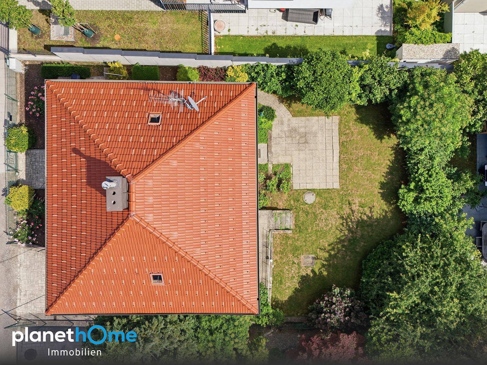 Luftaufnahme des Hauses mit rotem Ziegeldach, Garten und umliegender Bebauung.