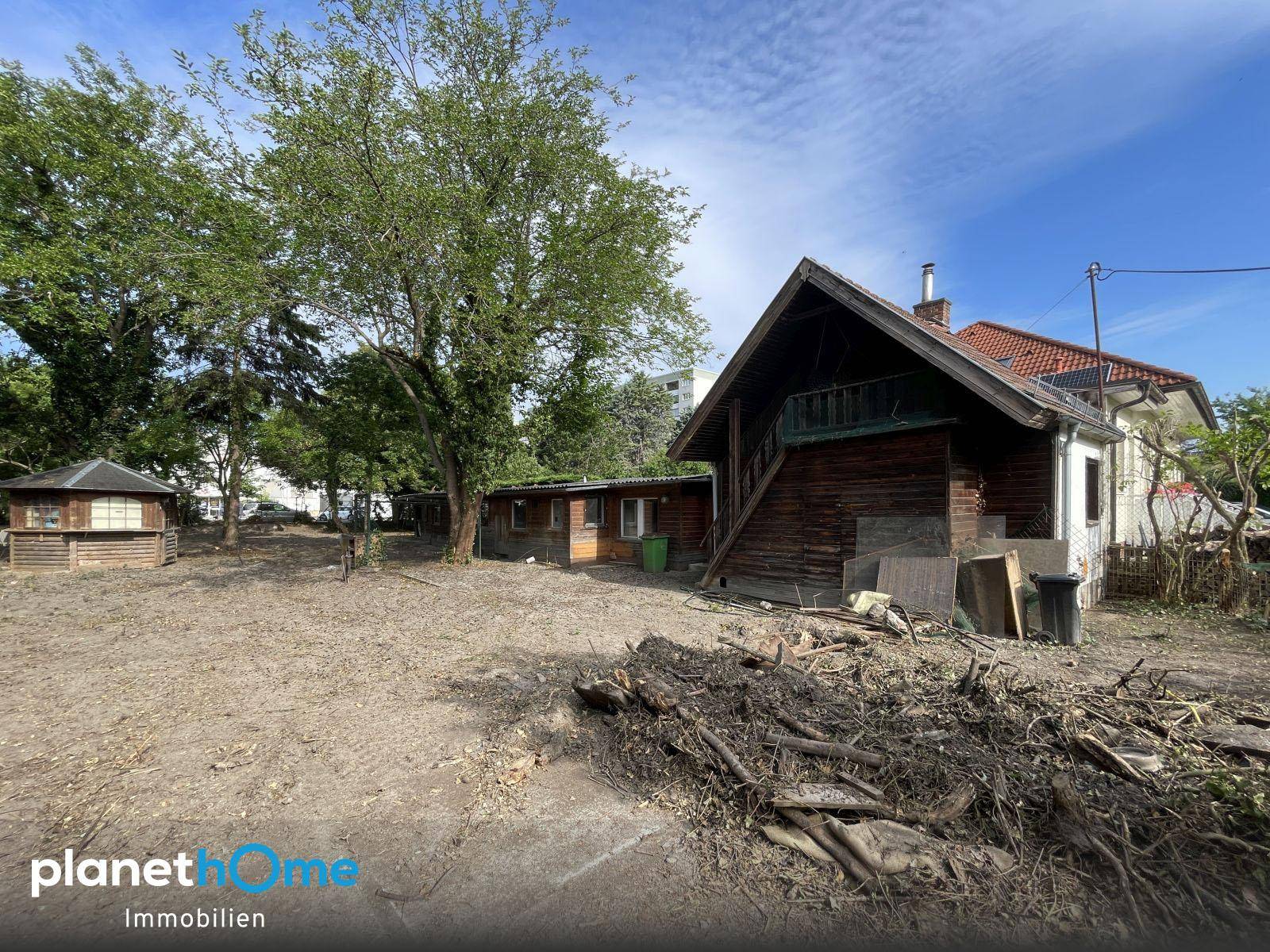 Rückansicht eines Hauses mit Holzfassade und großem, teilweise geräumtem Grundstück.