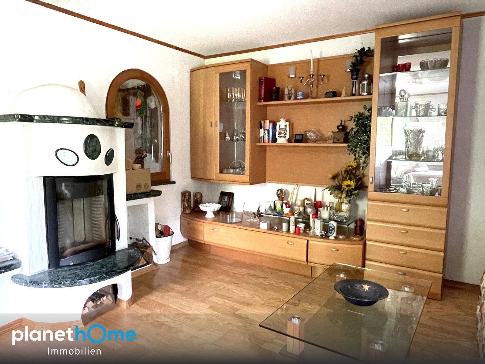 Wohnzimmer mit traditionellem Kachelofen, Holzmöbeln und einem Bogenfenster.