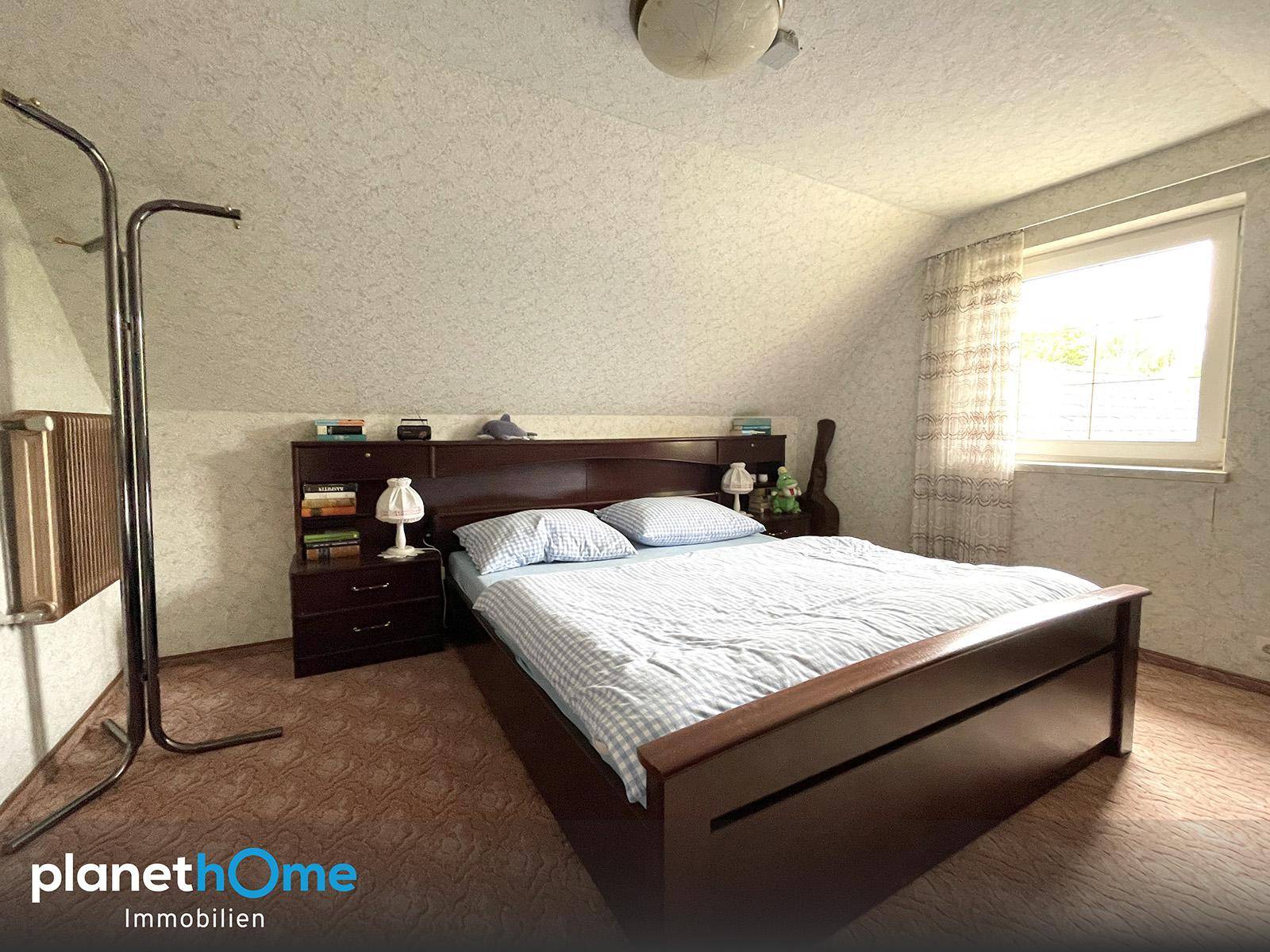 Schlafzimmer im Dachgeschoss mit Holzbett, Nachttischen und schrägen Decken.