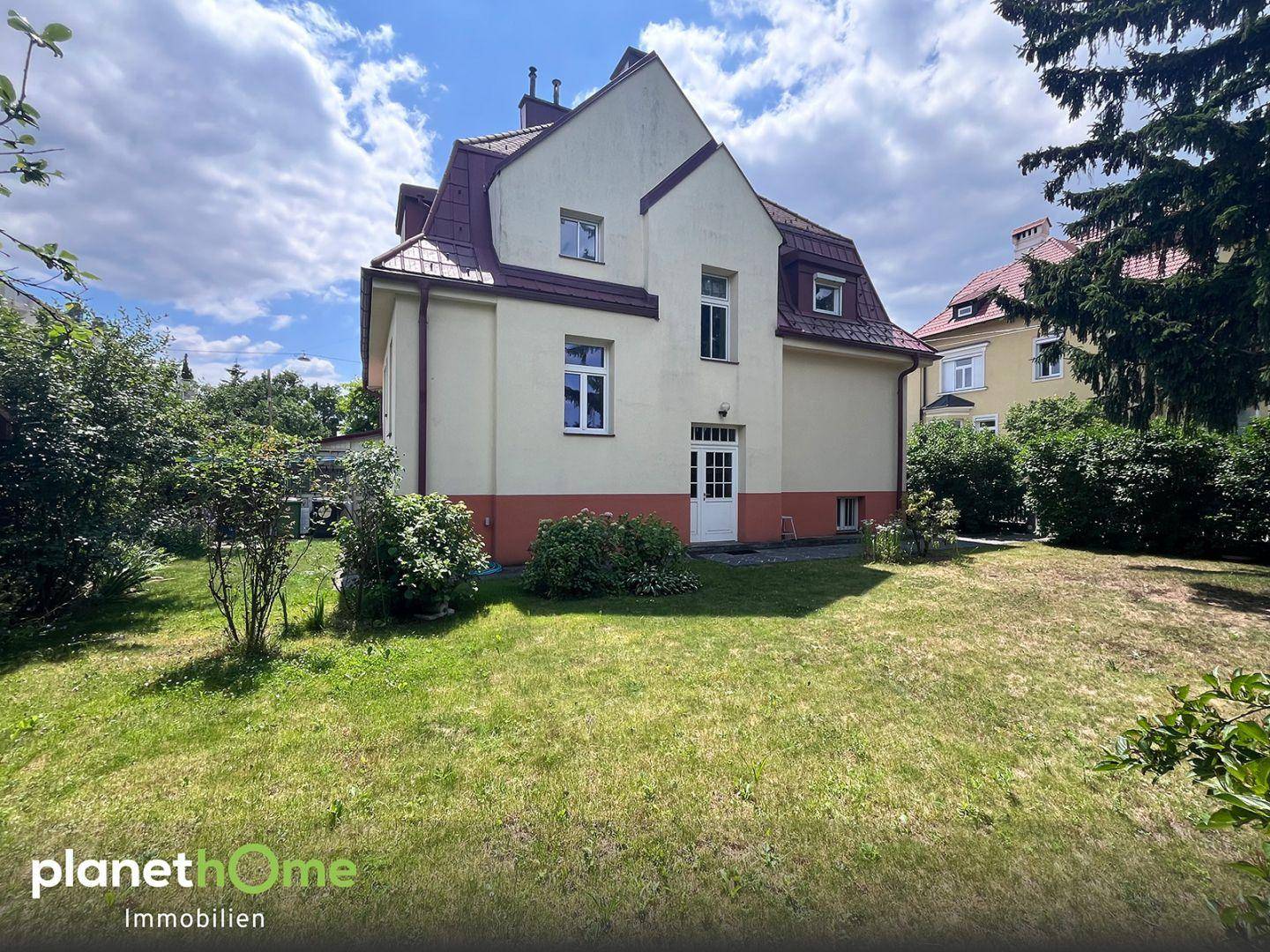 Ansicht des Hauses von der Gartenseite mit gepflegtem Rasen und üppiger Bepflanzung.