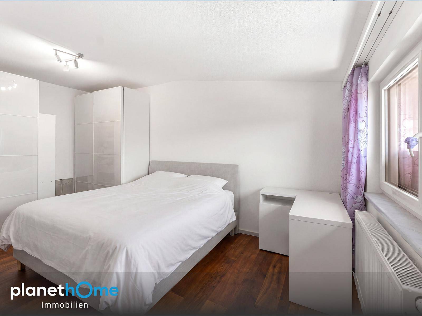 Gemütliches Schlafzimmer mit Doppelbett, weißen Kleiderschränken und Holzboden.