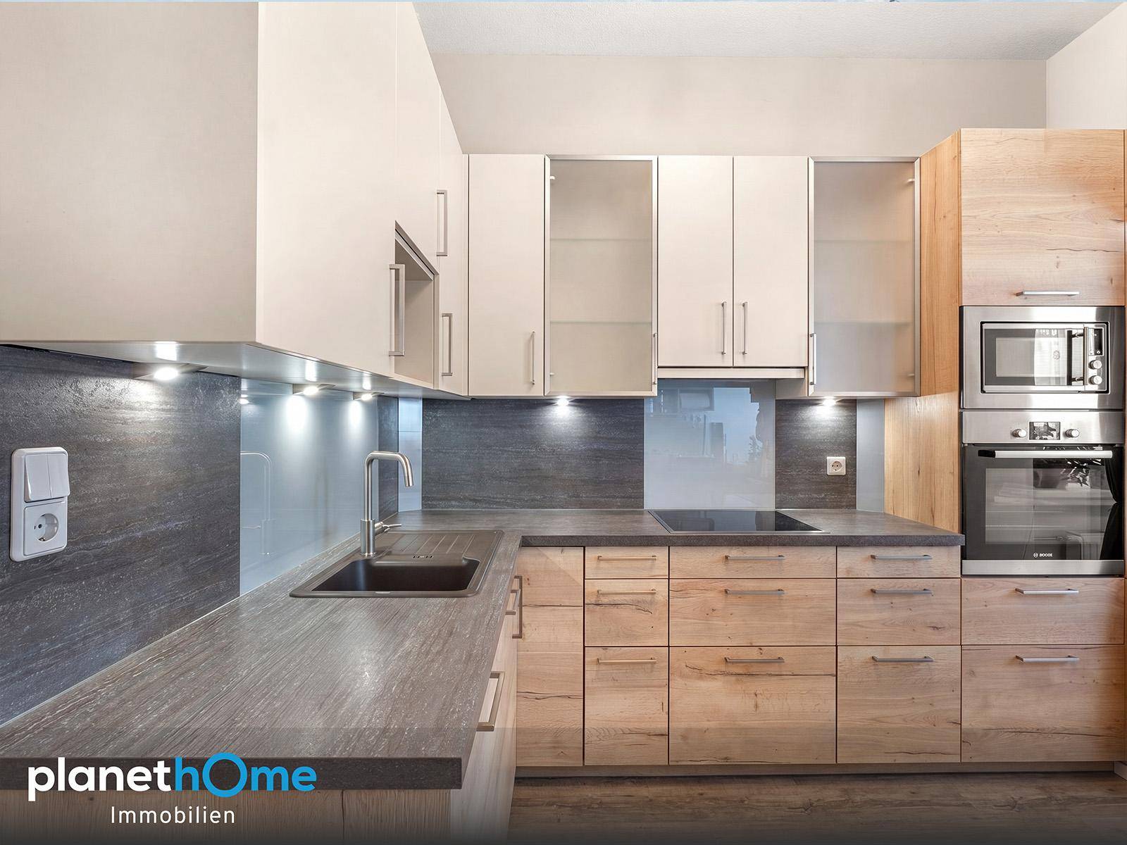 Moderne Einbauküche mit Holzfronten, hellen Oberschränken und integrierten Geräten.