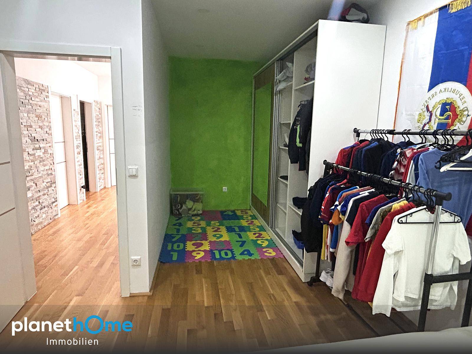 Heller Flur mit grüner Akzentwand, Holzboden und praktischem Kleiderschrank, bietet viel Stauraum.
