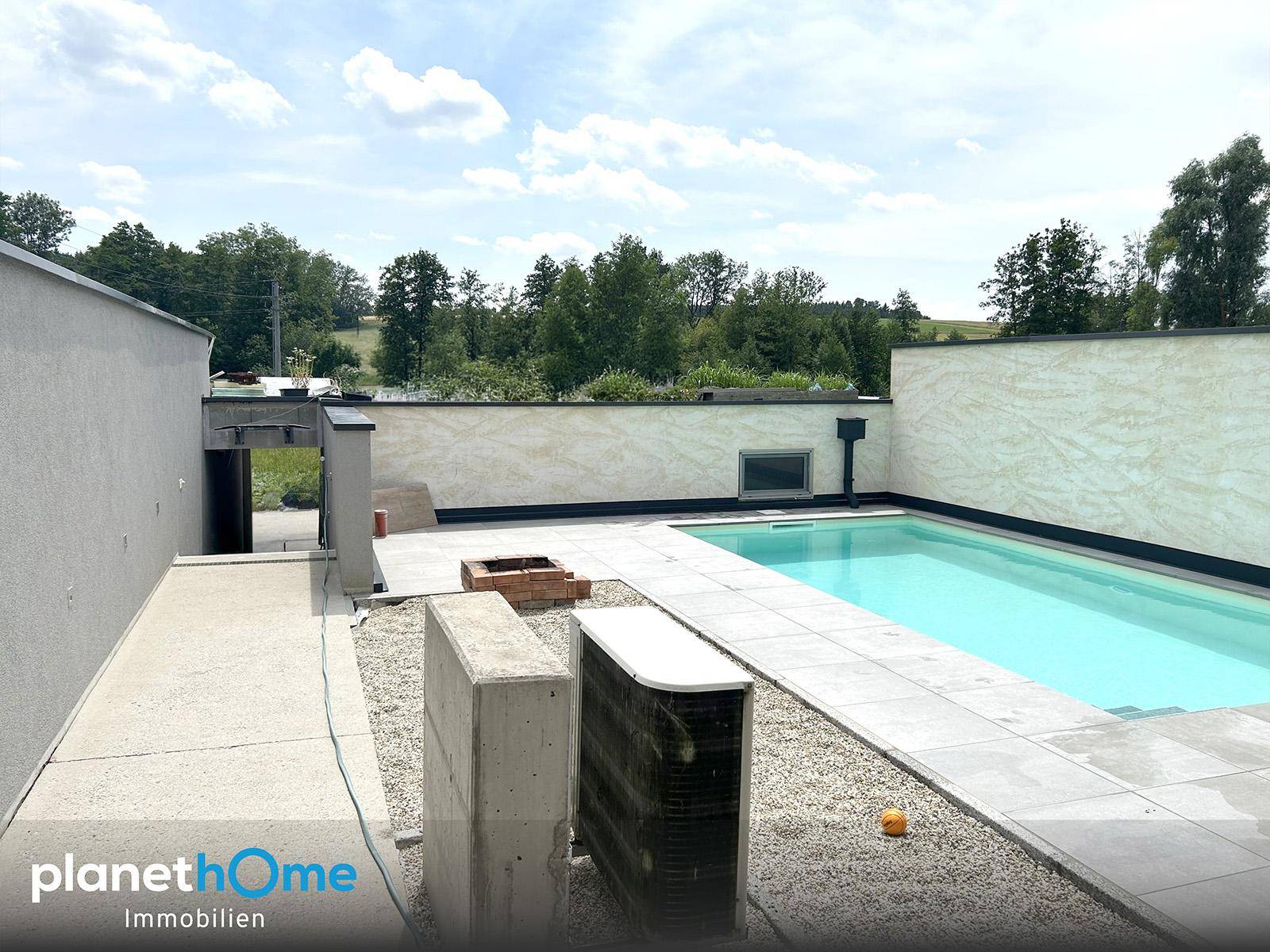 Hinterhof mit Swimmingpool, gefliester Fläche und Blick auf die umliegende grüne Landschaft.