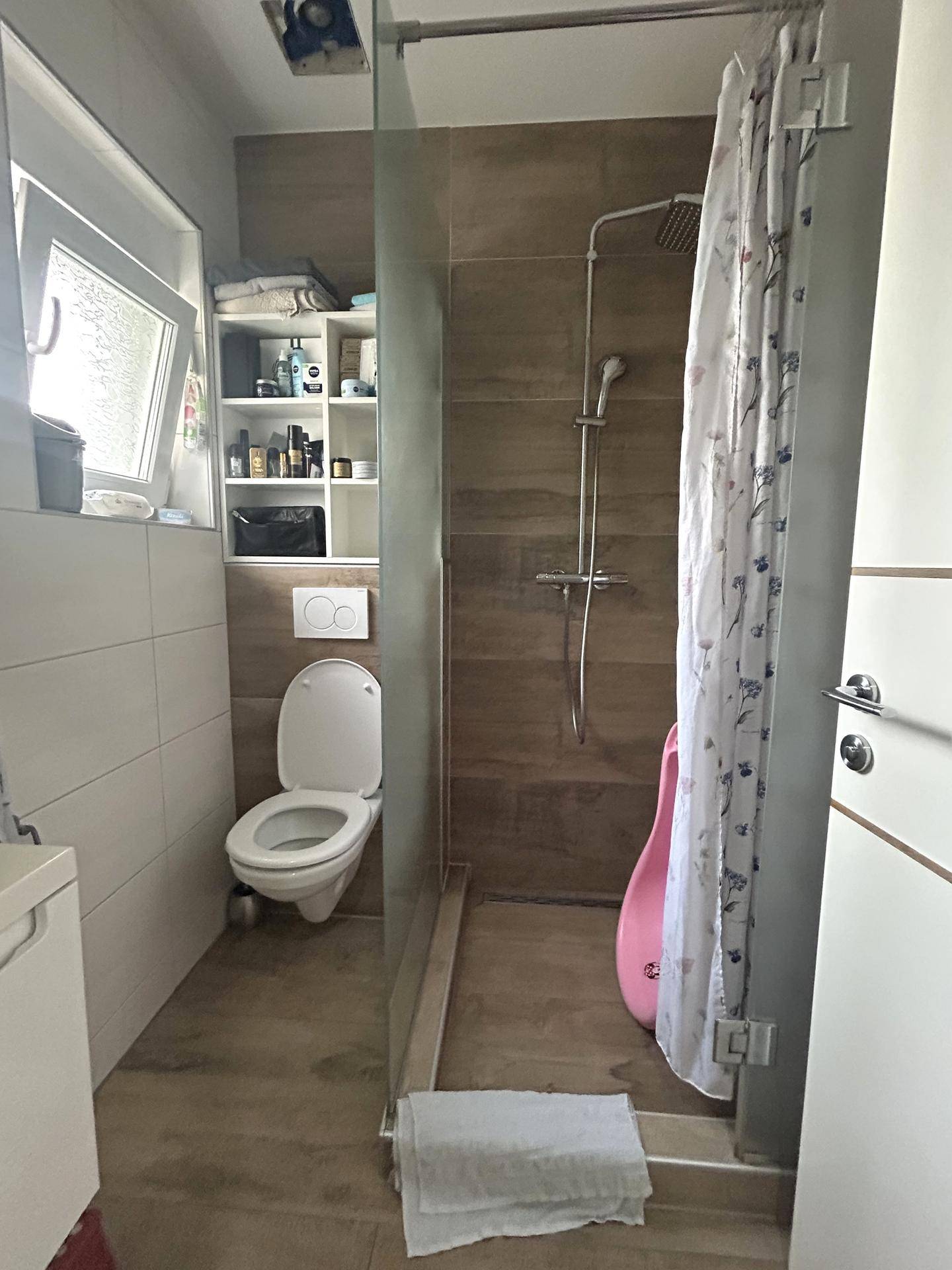 Kleines Badezimmer mit WC, begehbarer Dusche und Fenster, praktisch und hell gestaltet.