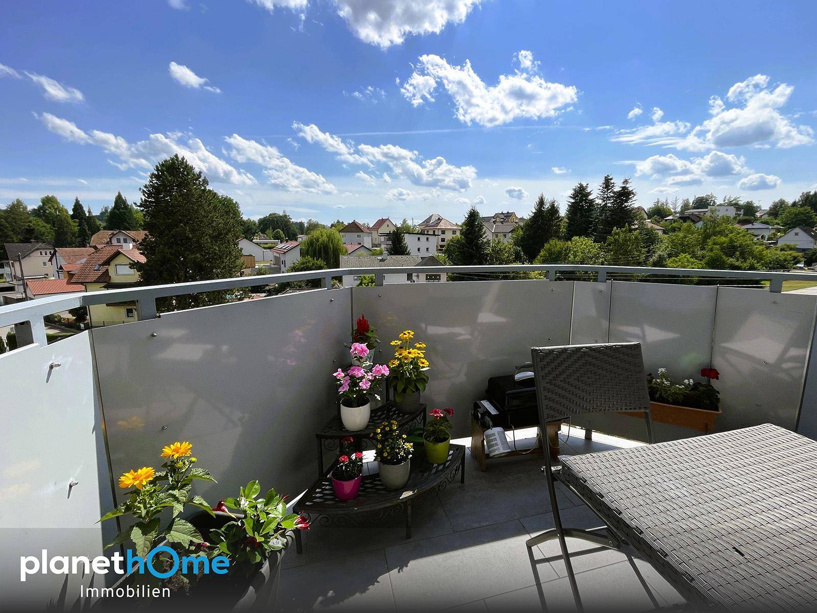 Heller Balkon mit Sitzgelegenheiten und Blumen, bietet einen schönen Ausblick auf die Umgebung.