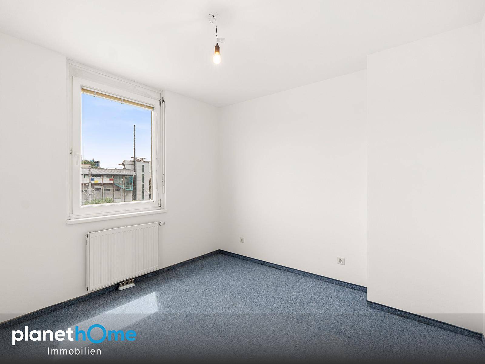 Geräumiges Schlafzimmer mit blauem Teppichboden und einem großen Fenster.