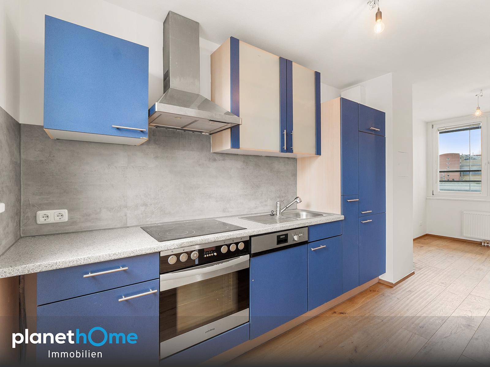 Moderne Einbauküche mit blauen Fronten, integrierten Geräten und heller Arbeitsplatte.
