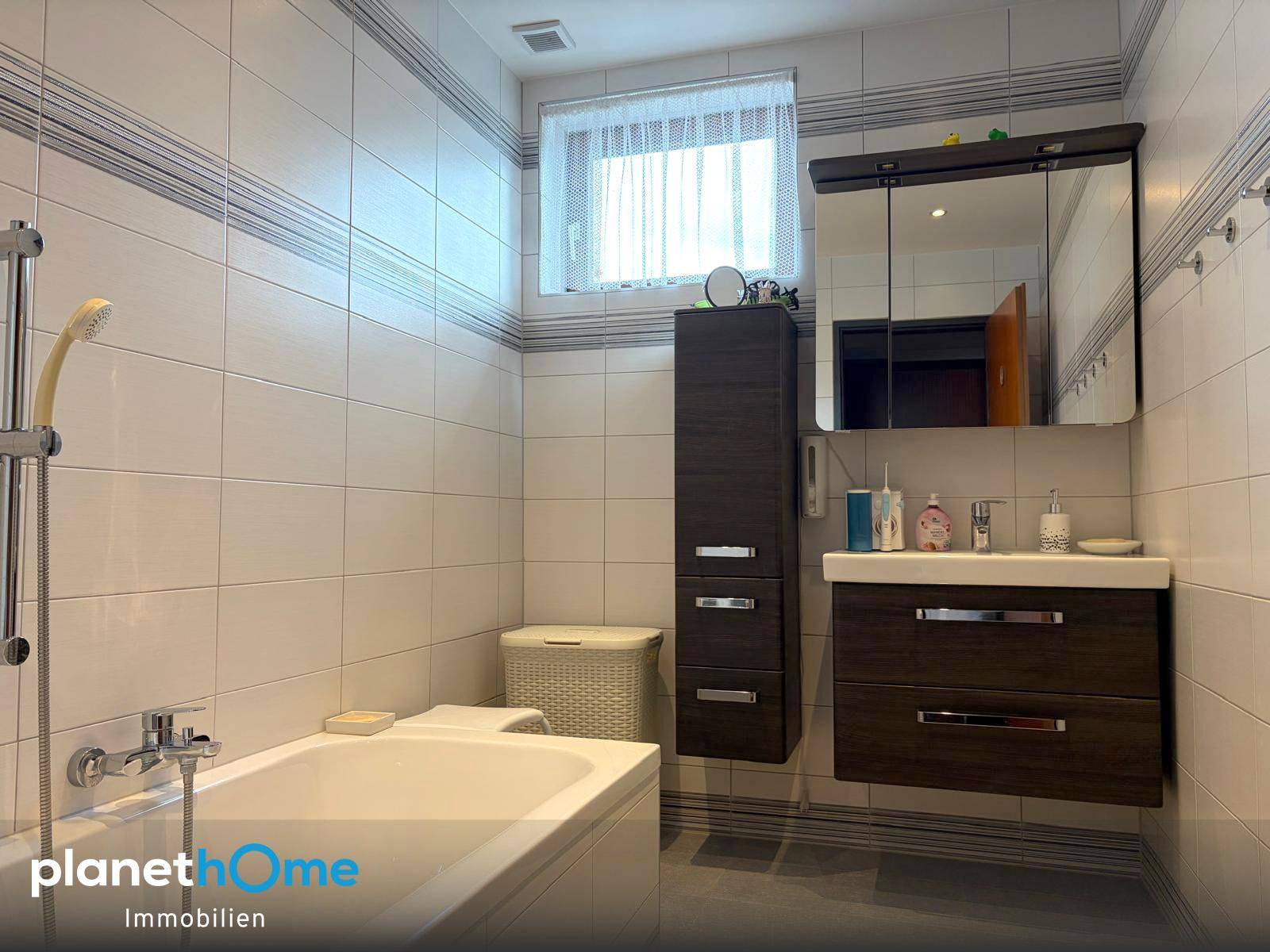 Modernes Badezimmer mit Badewanne, Waschtischunterschrank und Spiegelschrank.
