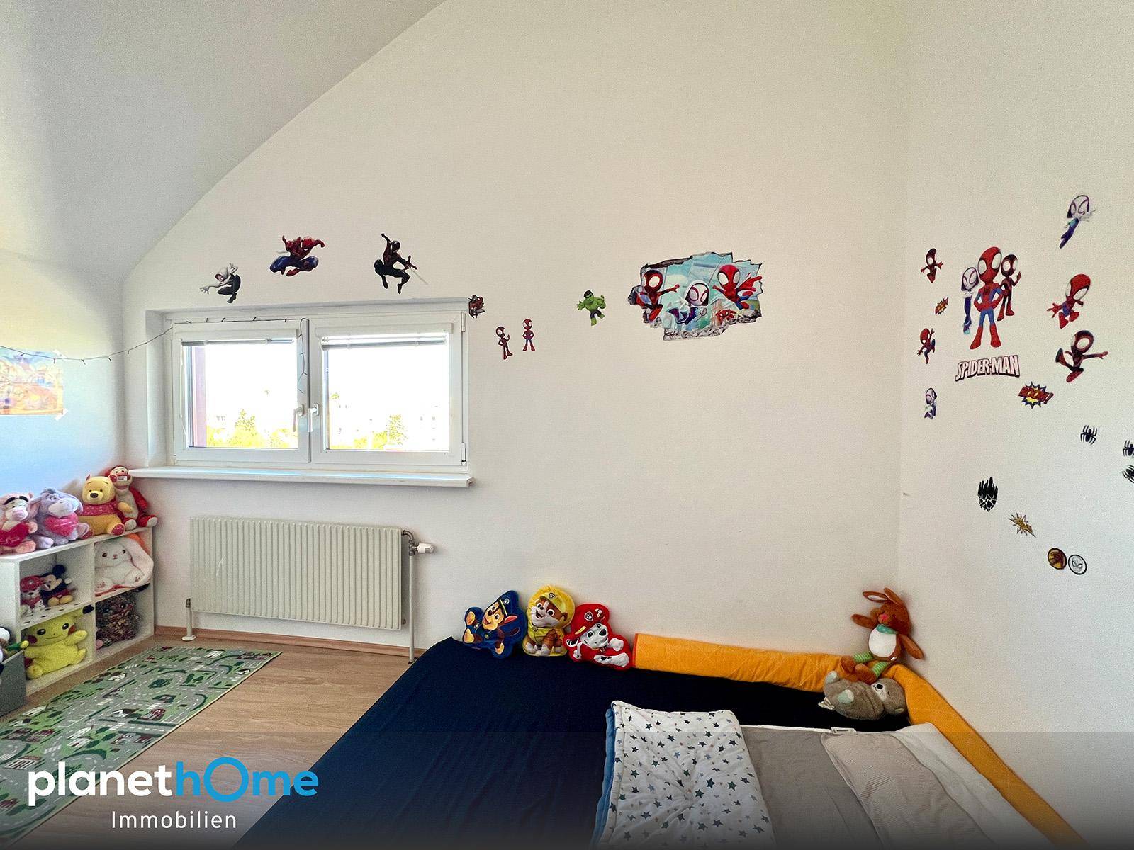 Kinderzimmer mit Laminatboden, Spiderman-Wandstickern und Spielzeug.