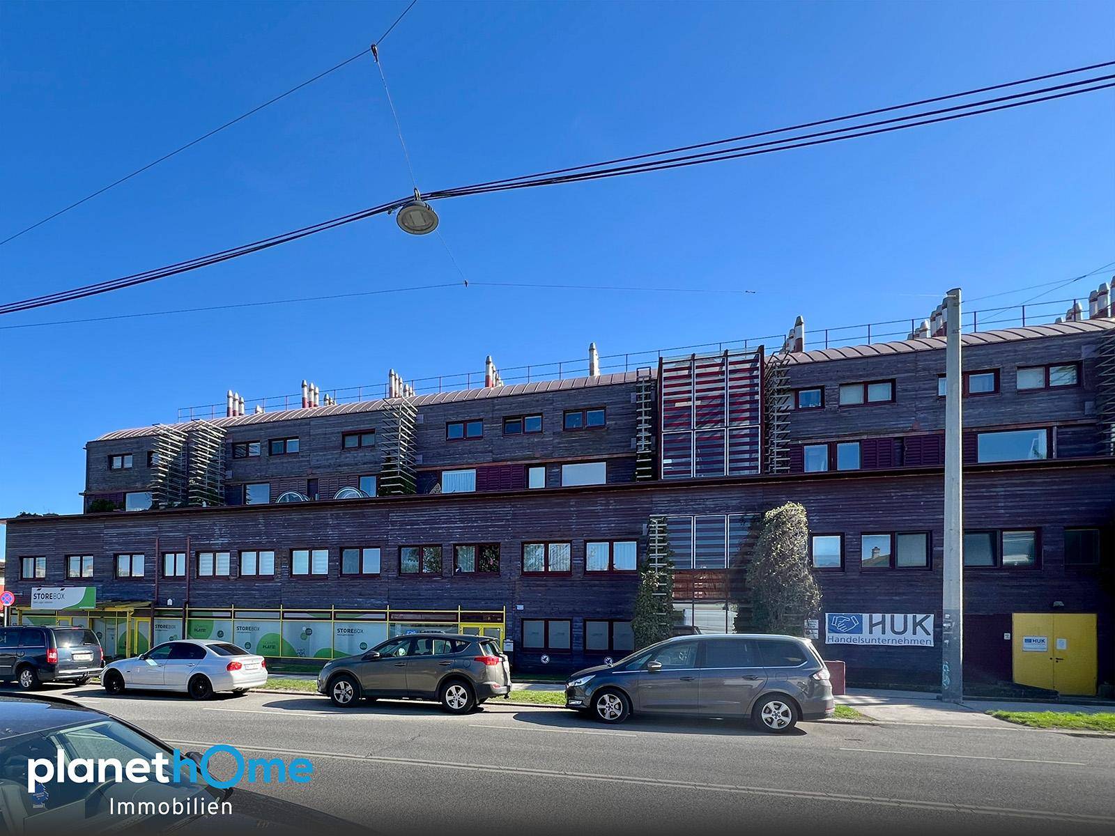Mehrstöckiges Gebäude mit moderner Fassade und vielen Fenstern an einer Straße.