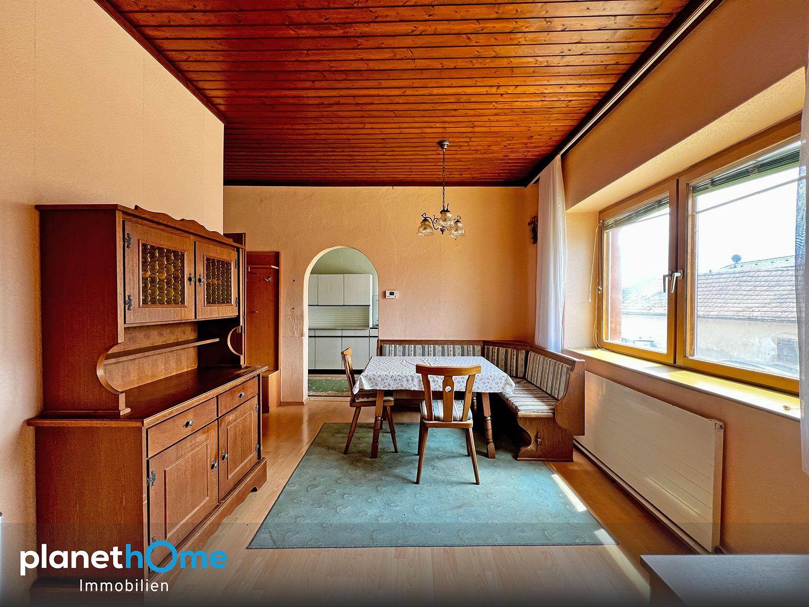 Gemütliches Esszimmer mit Holzdecke, traditionellen Möbeln und einem Durchgang zur Küche.
