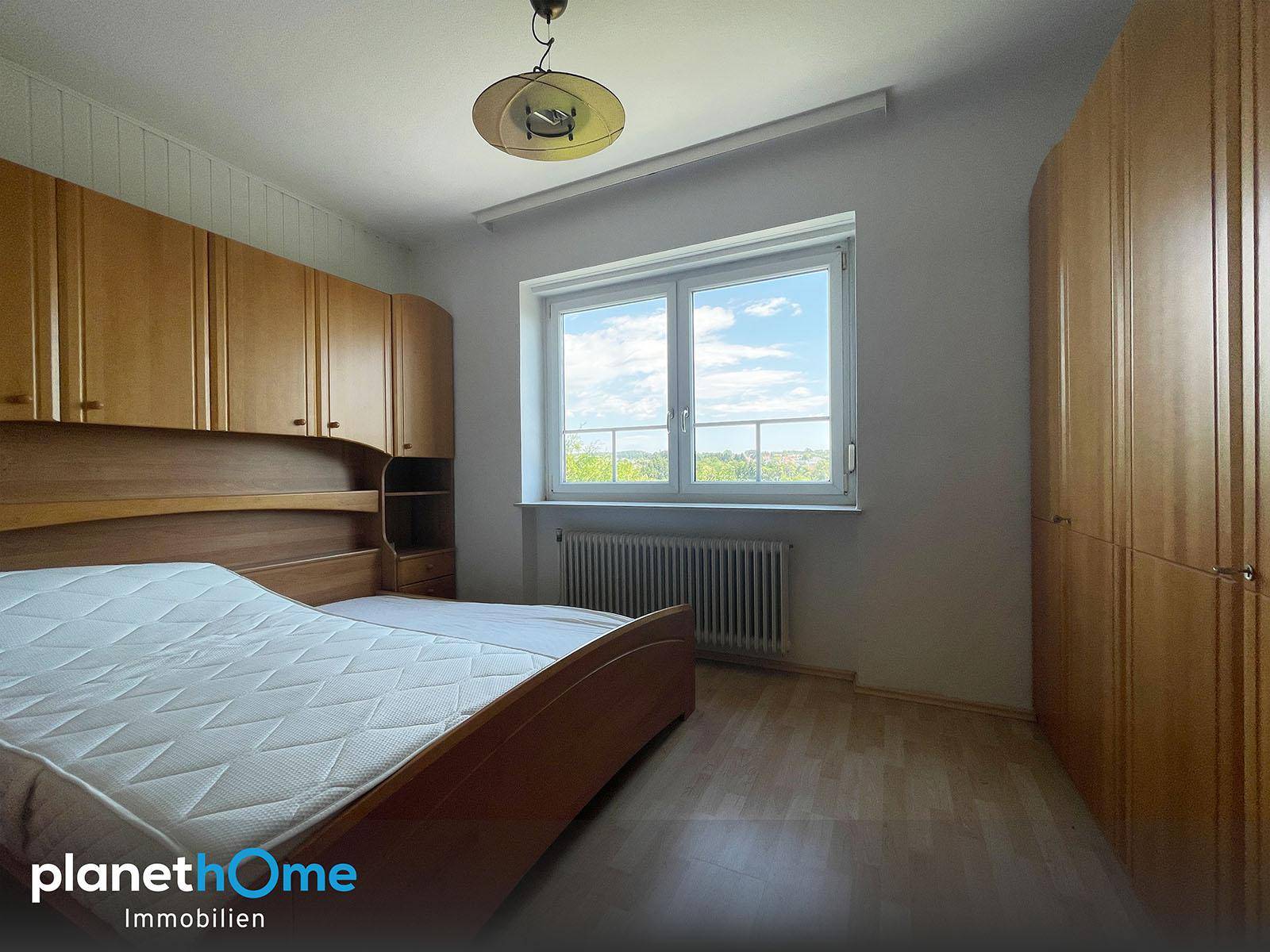 Gemütliches Schlafzimmer mit Doppelbett, Einbauschränken und Blick ins Grüne.