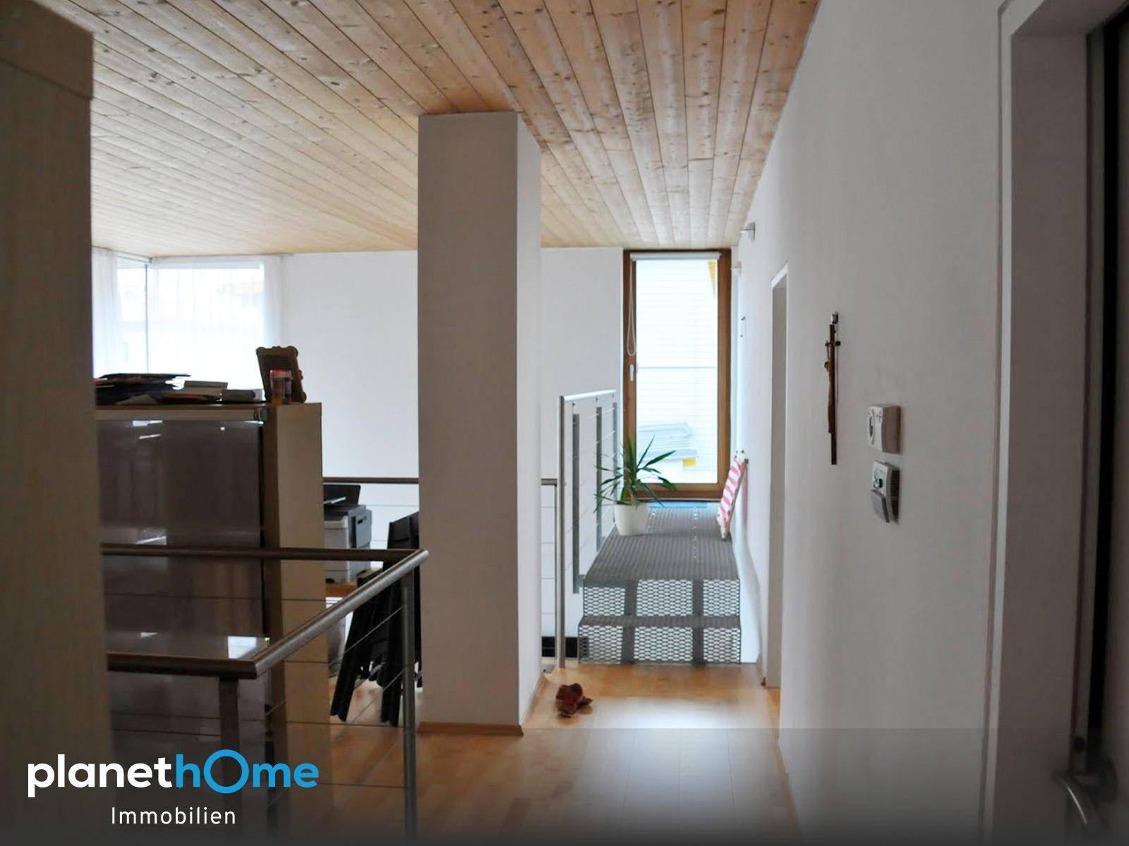 Heller Flur mit Holzboden, Holzdecke und Blick auf die Treppe, die in die obere Etage führt.