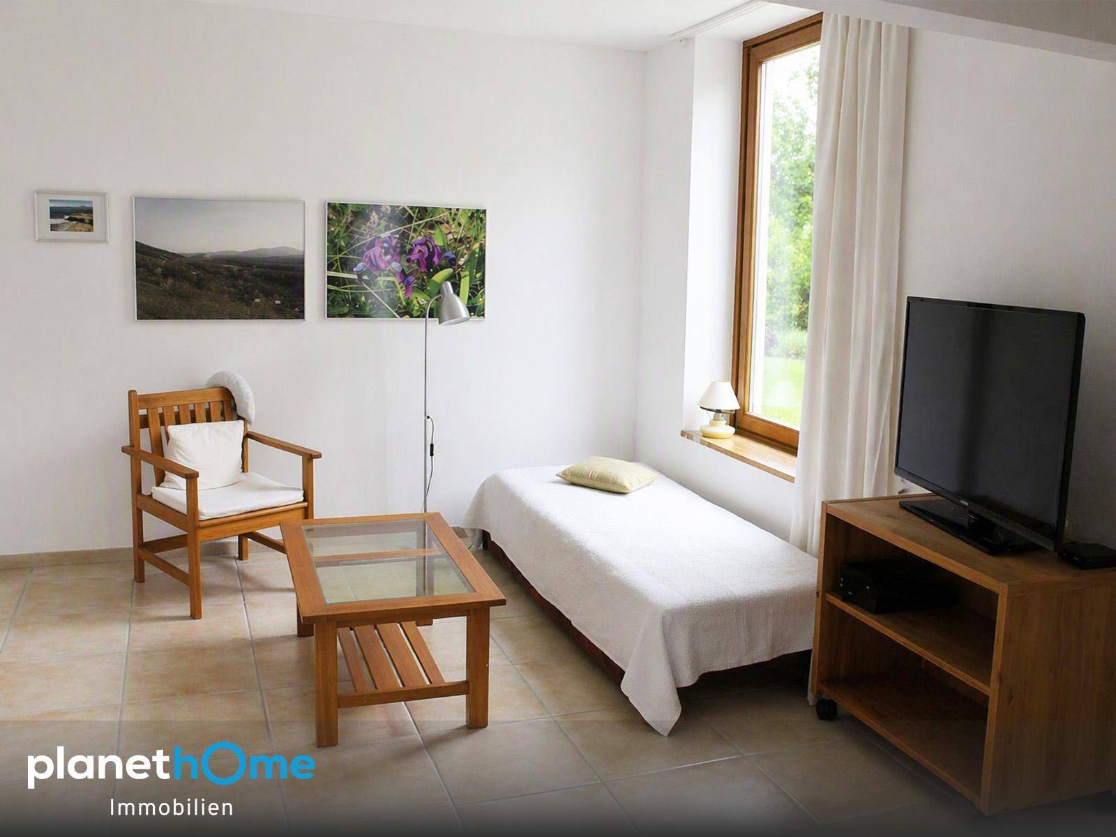 Gemütliches Schlafzimmer mit Einzelbett, Fliesenboden und einem hohen Fenster für viel Licht.