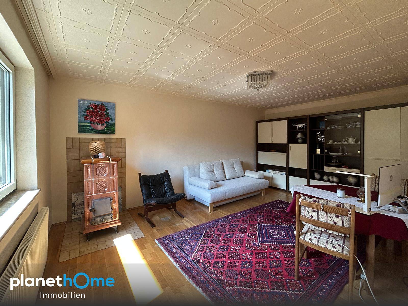Wohnzimmer mit Holzofen, gemusterter Decke und traditionellen Möbeln, bietet eine gemütliche Atmosphäre.