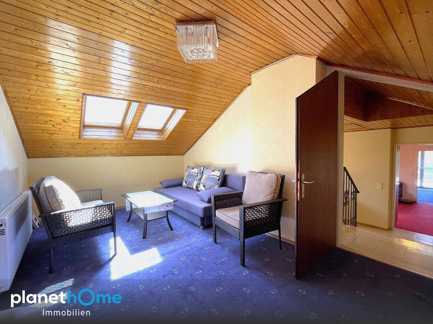 Gemütliches Dachzimmer mit Holzverkleidung, Dachfenstern und einer einladenden Sitzecke.
