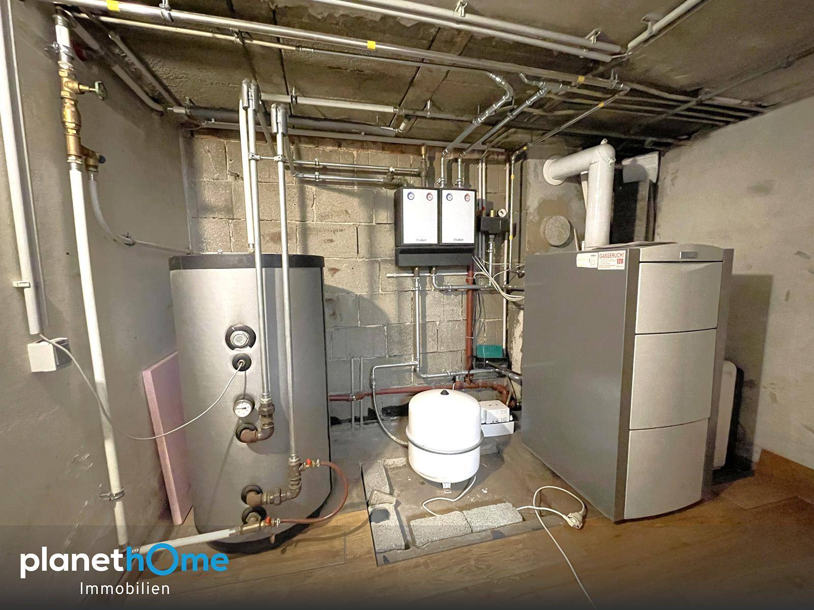 Heizungsraum im Keller mit Warmwasserspeicher und Heizungsanlage, funktional und gut zugänglich.