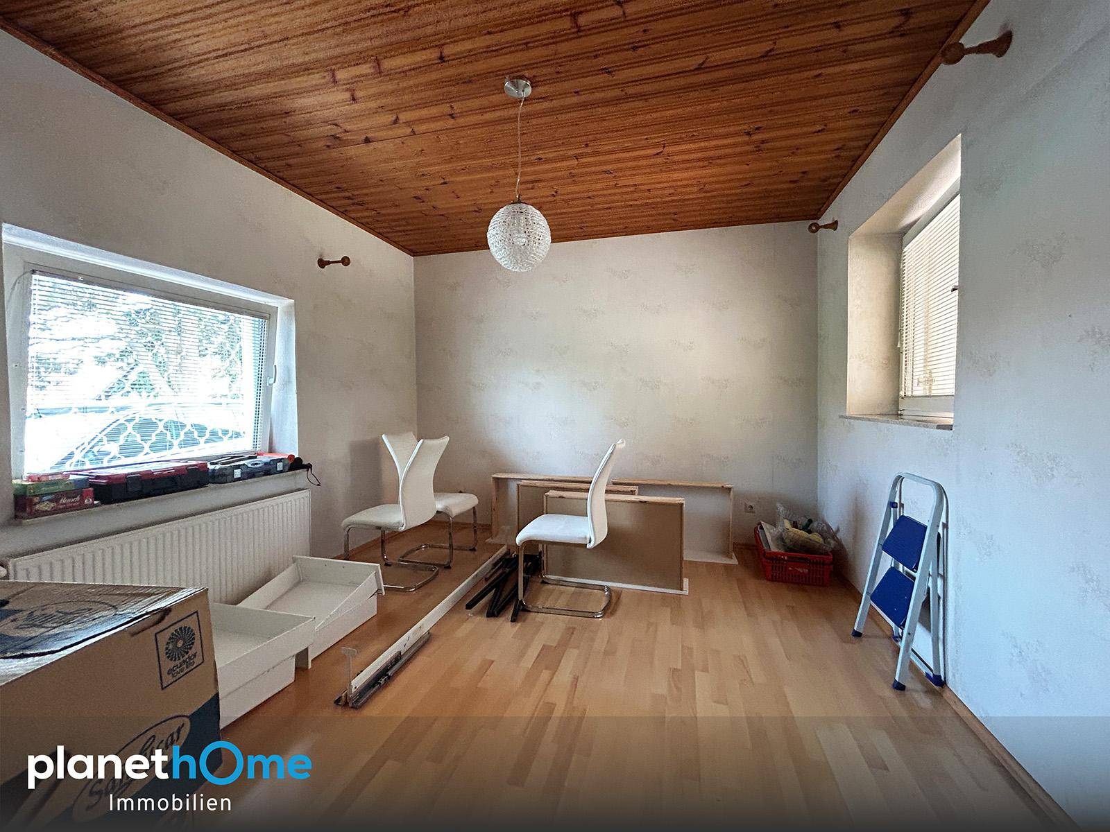 Geräumiger Raum mit Holzboden und Holzdecke, hell durch zwei Fenster, ideal zur individuellen Einrichtung.
