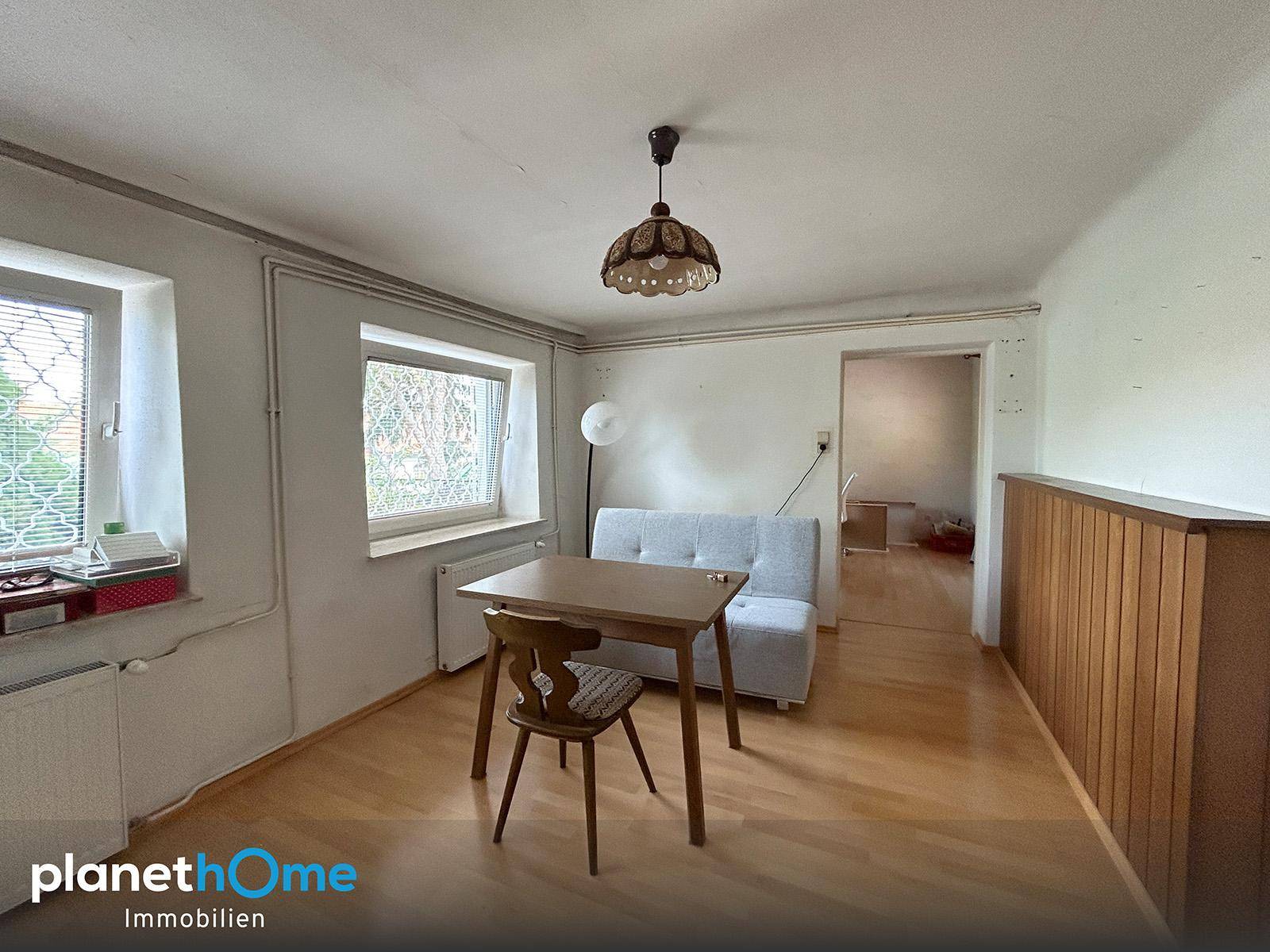 Heller Wohnraum mit Holzboden, kleinem Tisch und Sofa, bereit für persönliche Gestaltung.