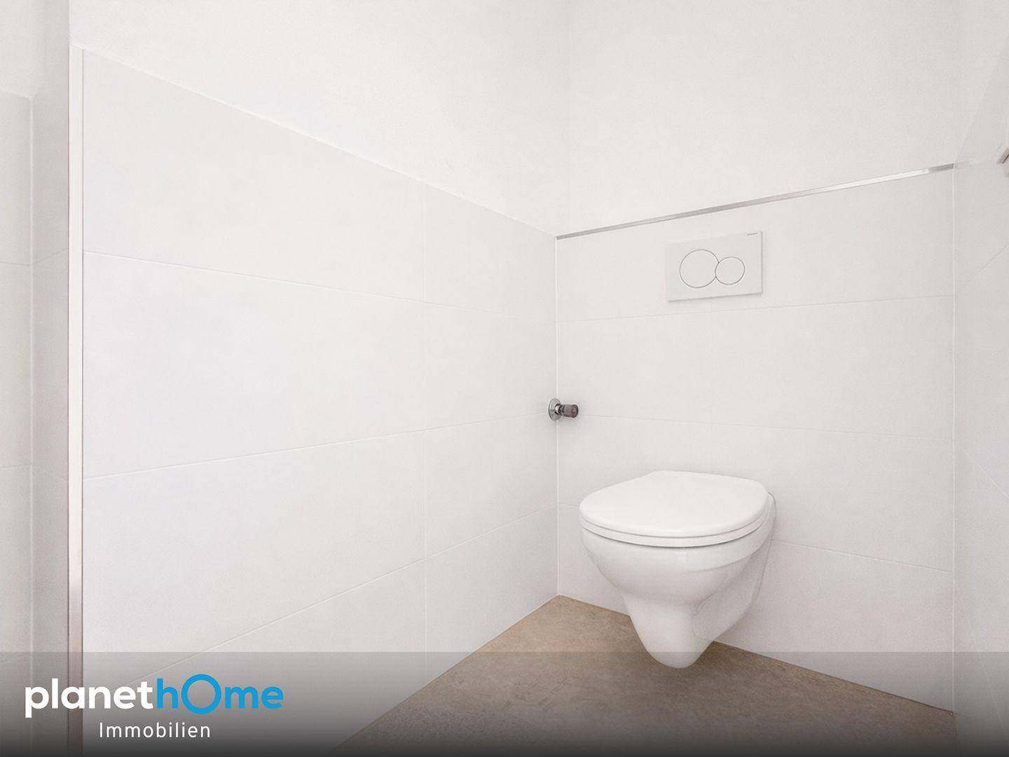 Separates WC mit wandhängender Toilette und weißen Fliesen an den Wänden.