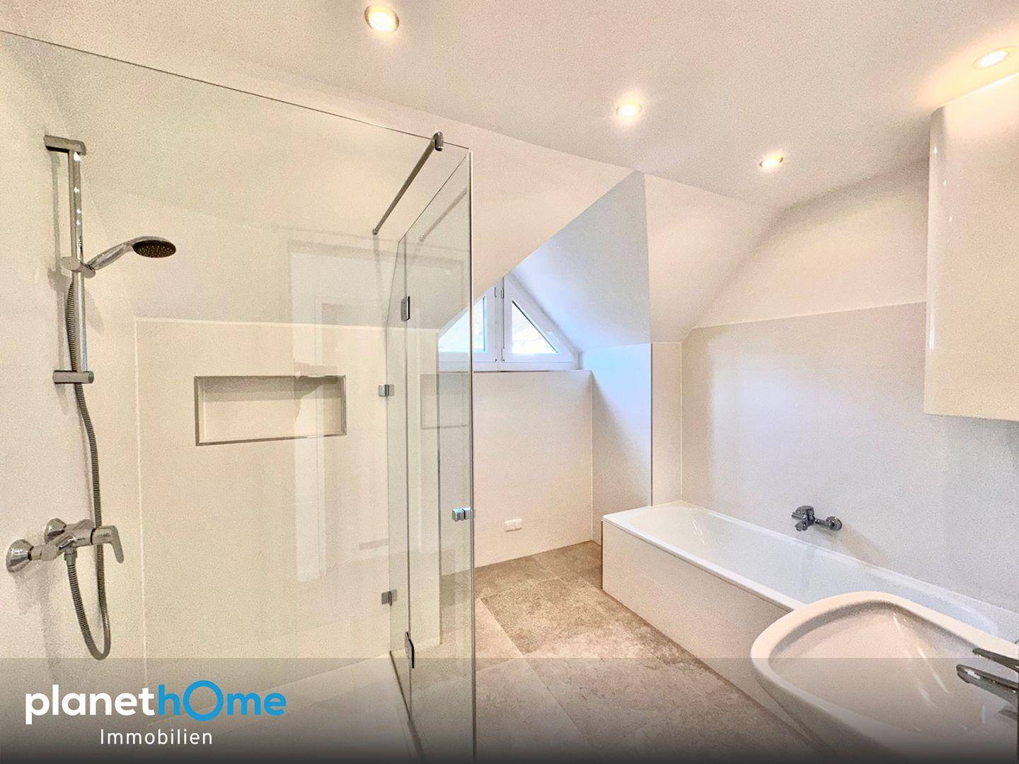 Modernes Badezimmer mit begehbarer Dusche, Badewanne und Dachfenster unter der Dachschräge.