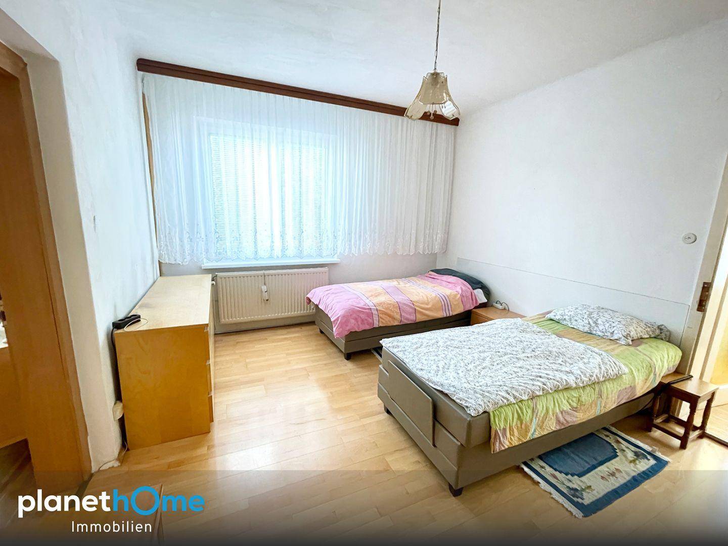 Kinder- oder Gästezimmer mit zwei Einzelbetten, Laminatboden und großem Fenster.