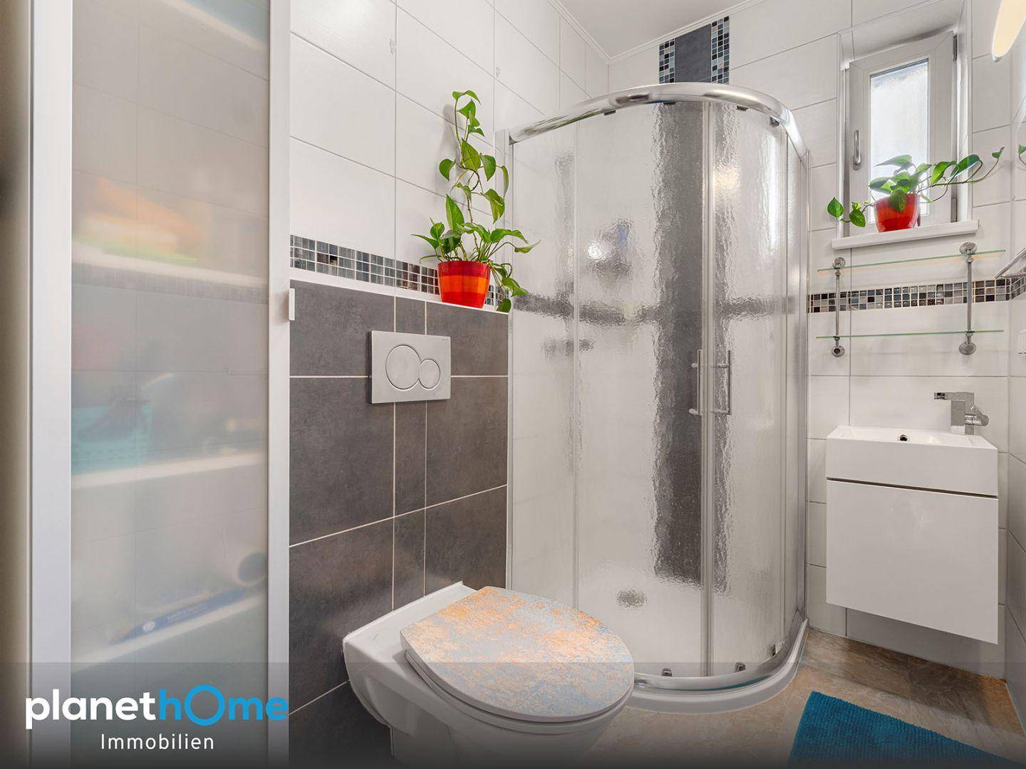 Funktionales Badezimmer mit Duschkabine, WC und Fenster für Tageslicht.