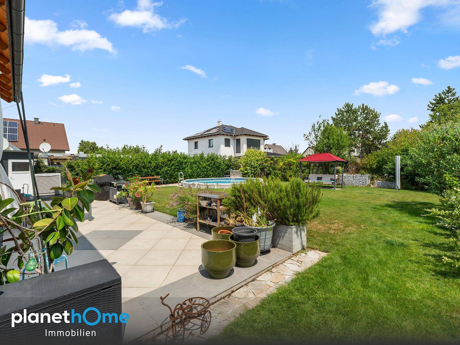 Gepflegter Gartenbereich mit Terrasse, Grillplatz und Blick auf den Pool.