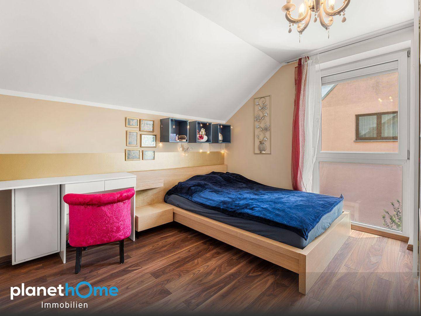Gemütliches Schlafzimmer mit Holzbett, Dachschräge und großem Fenster.