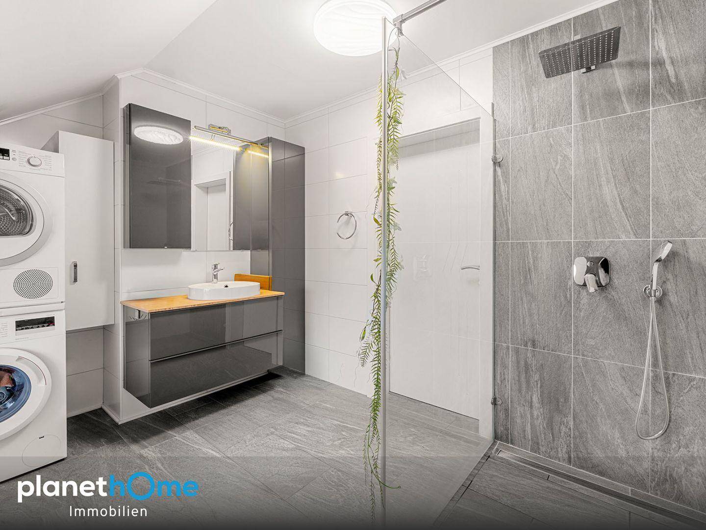 Modernes Badezimmer mit großer Dusche, Waschmaschine und Trockner.
