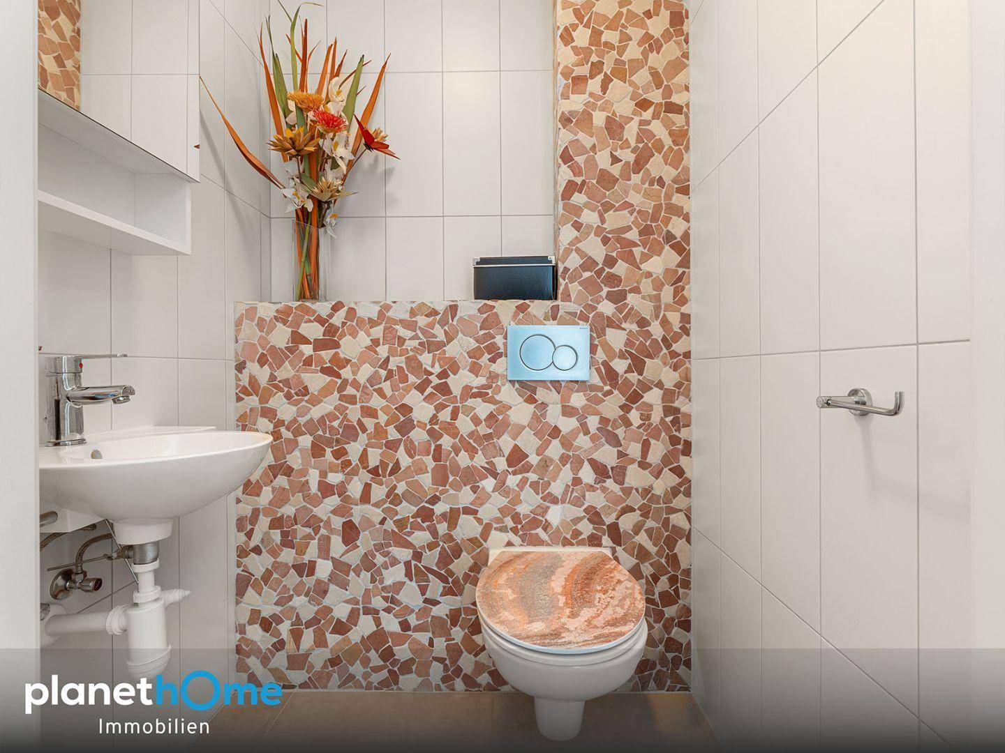 Kleines Gäste-WC mit Mosaikfliesen und modernem Waschbecken.