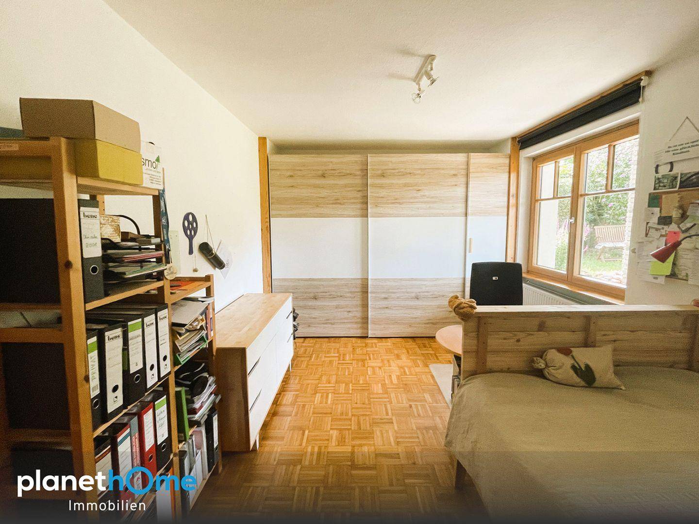 Schlafzimmer mit Holzbett, integriertem Kleiderschrank und Parkettboden, hell und freundlich.