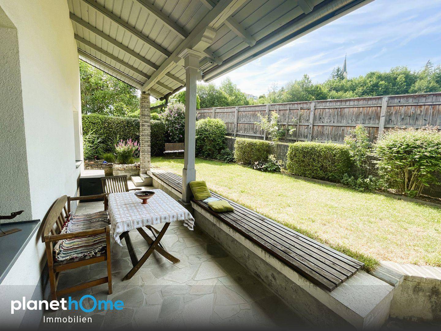 Überdachte Terrasse mit Sitzgelegenheiten und direktem Zugang zum gepflegten Garten.