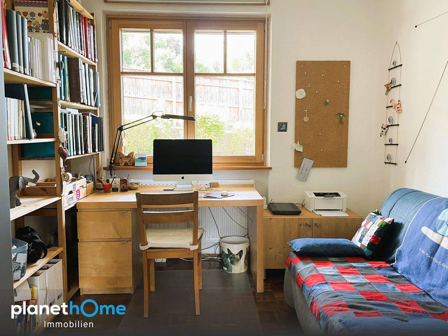 Funktionales Arbeitszimmer mit Schreibtisch, Büchern und Blick in den ruhigen Gartenbereich.