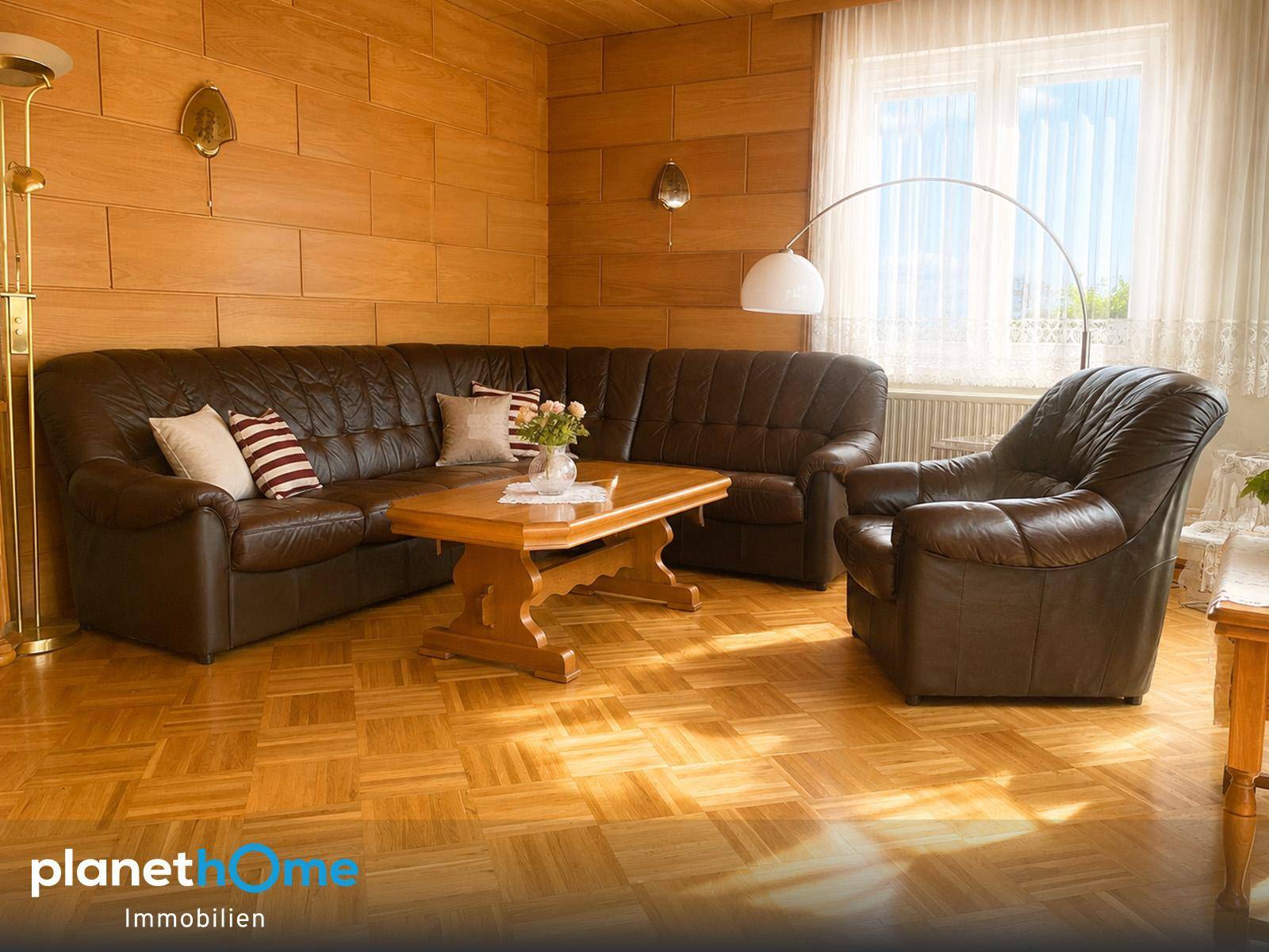 Traditionelles Wohnzimmer mit Holzvertäfelung, Ledersofa und Parkettboden.
