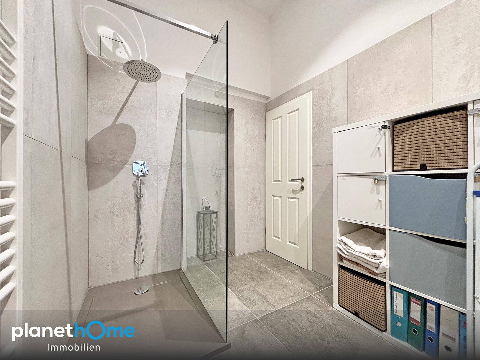 Nahaufnahme einer modernen begehbaren Dusche mit Regenduschkopf und Fliesenboden.