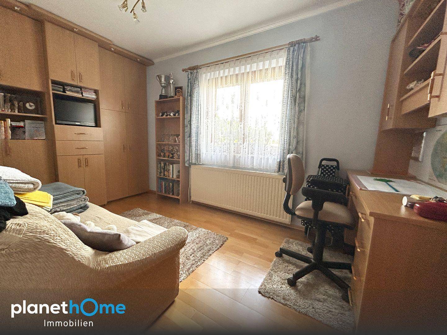 Schlafzimmer mit integrierten Holzschränken, Schreibtisch und Parkettboden.