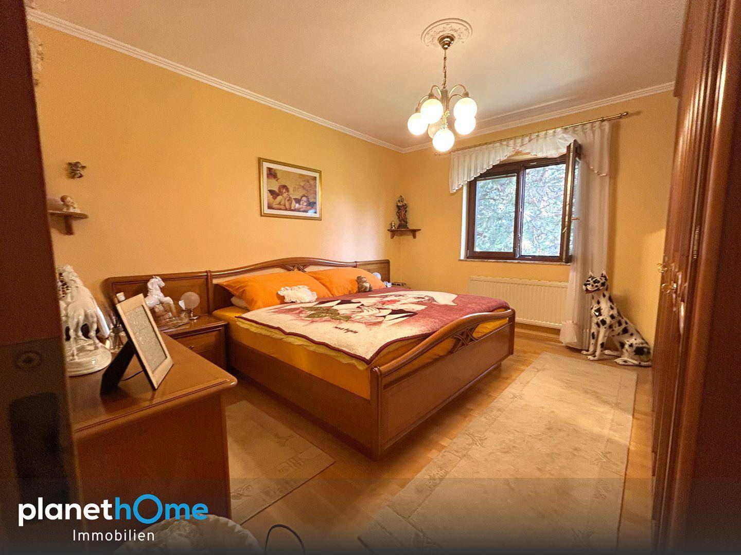 Helles Schlafzimmer mit Doppelbett, Holzmöbeln und Parkettboden.
