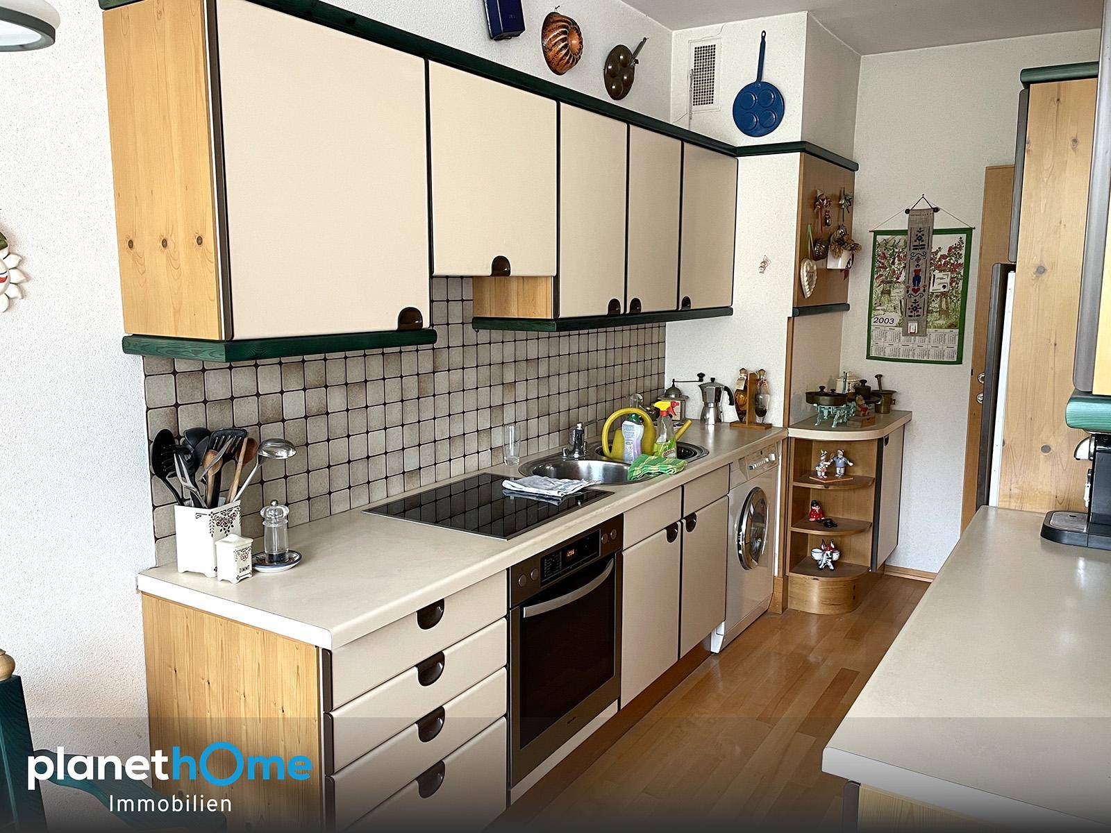 Traditionelle Küche mit beigen Schränken, Holzdetails und integrierten Geräten, inklusive Waschmaschine.
