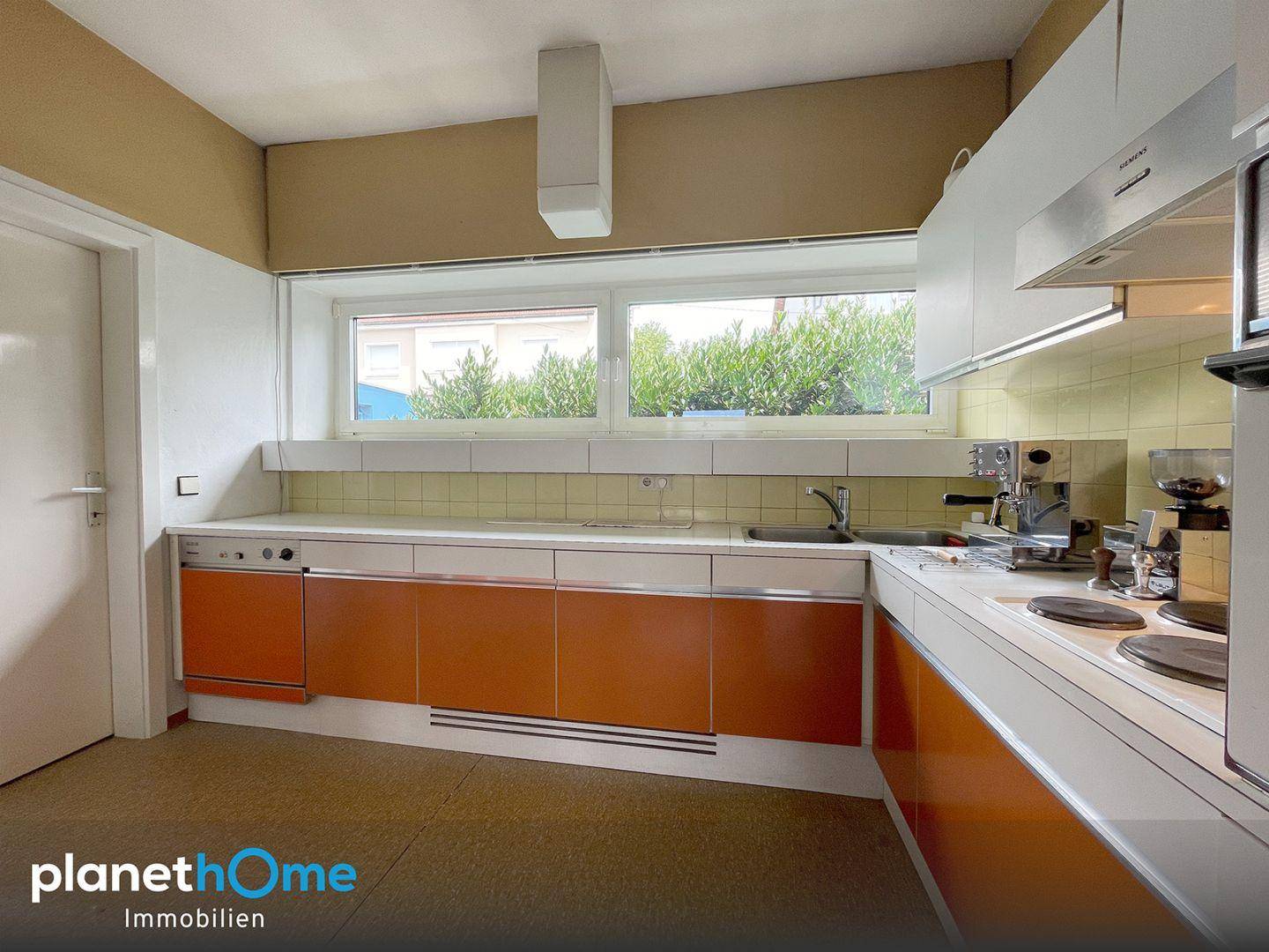 Küche im Retro-Stil mit orangefarbenen Fronten, Spülmaschine und Fensterblick.