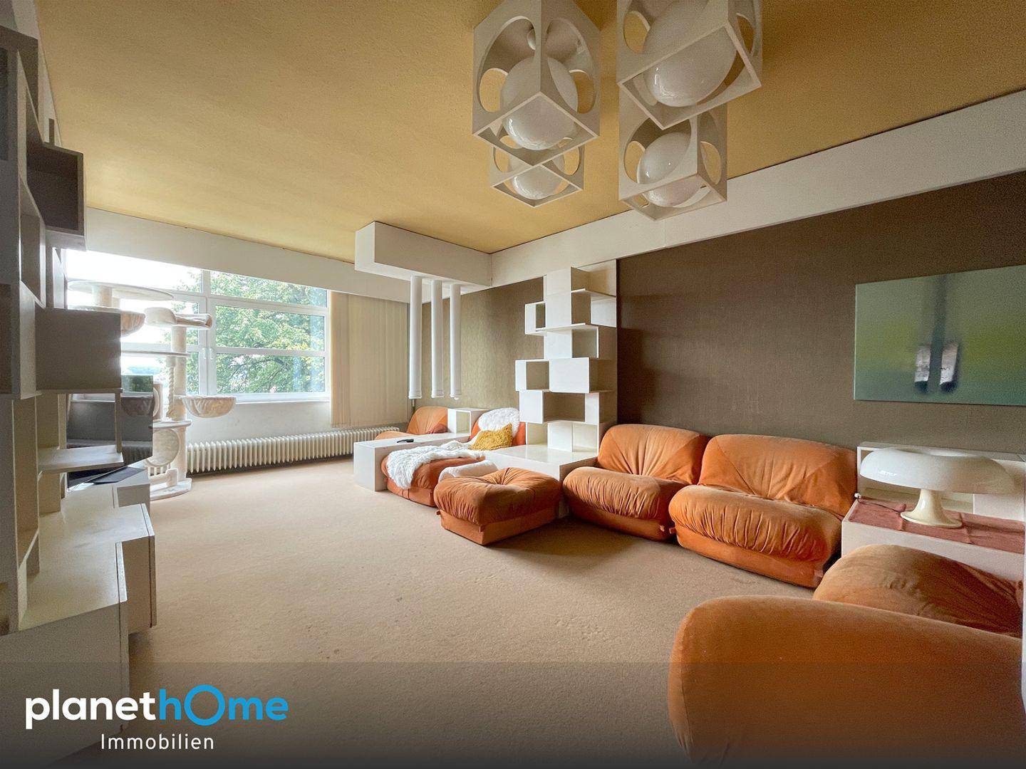 Geräumiges Wohnzimmer im Retro-Stil mit orangefarbenen Sofas und einzigartigen Deckenleuchten.