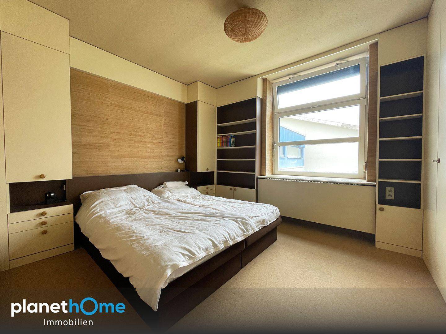 Schlafzimmer mit Doppelbett, Einbauschränken und großem Fenster für viel Licht.