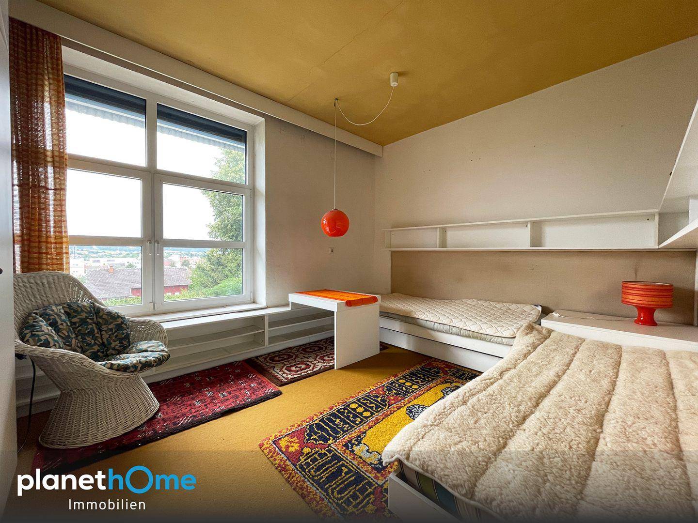 Helles Schlafzimmer mit zwei Einzelbetten, Teppichboden und Blick ins Grüne.