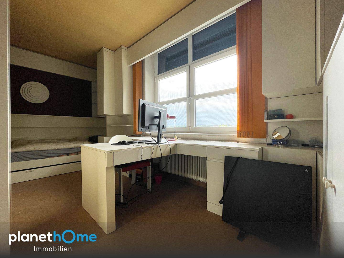Schlafzimmer mit integriertem Schreibtischbereich und weitem Ausblick durch das Fenster.