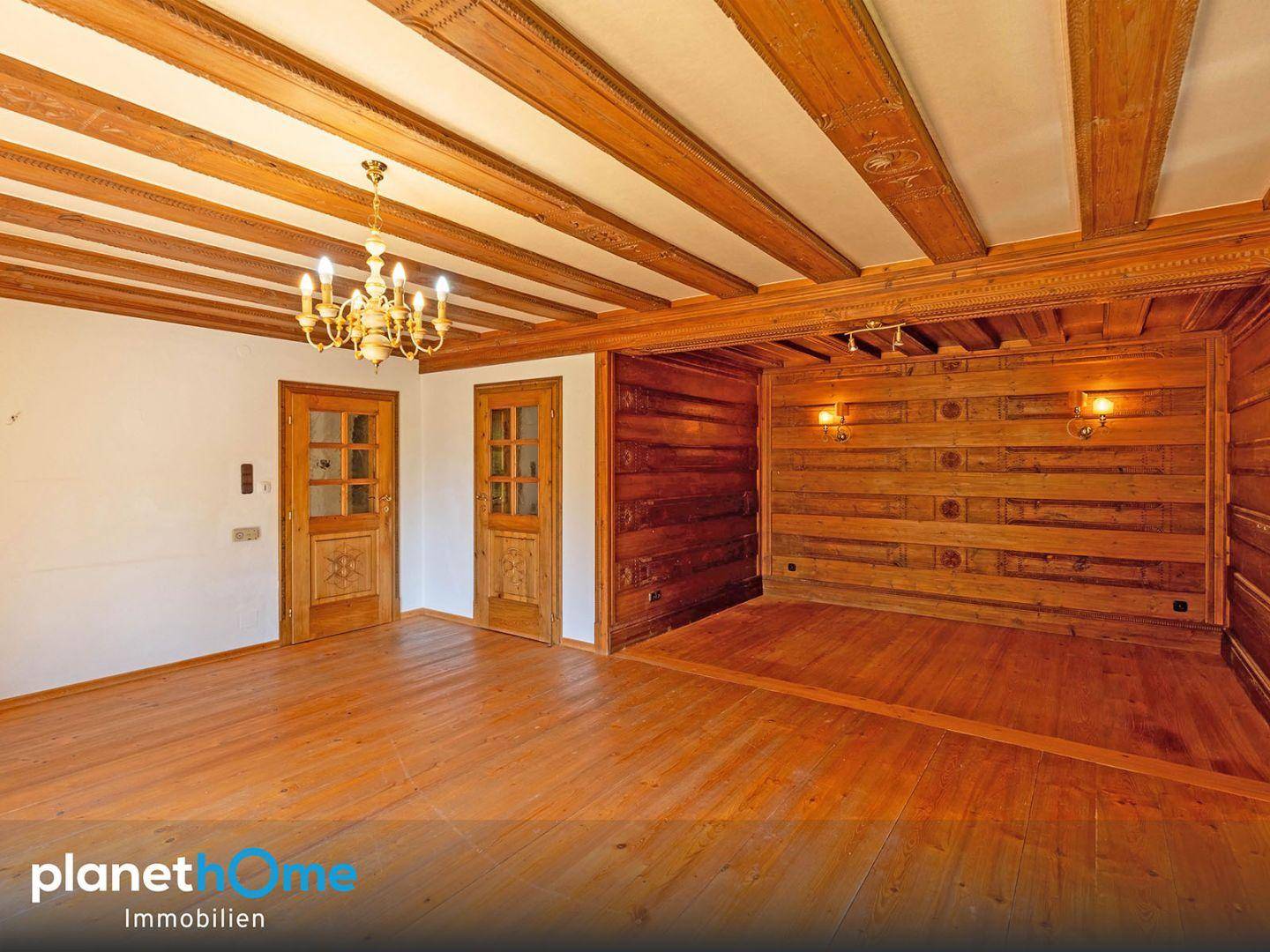 Wohnzimmer mit beeindruckender Holzbalkendecke, Holzwänden und traditionellem Holzboden, klassisch eingerichtet.