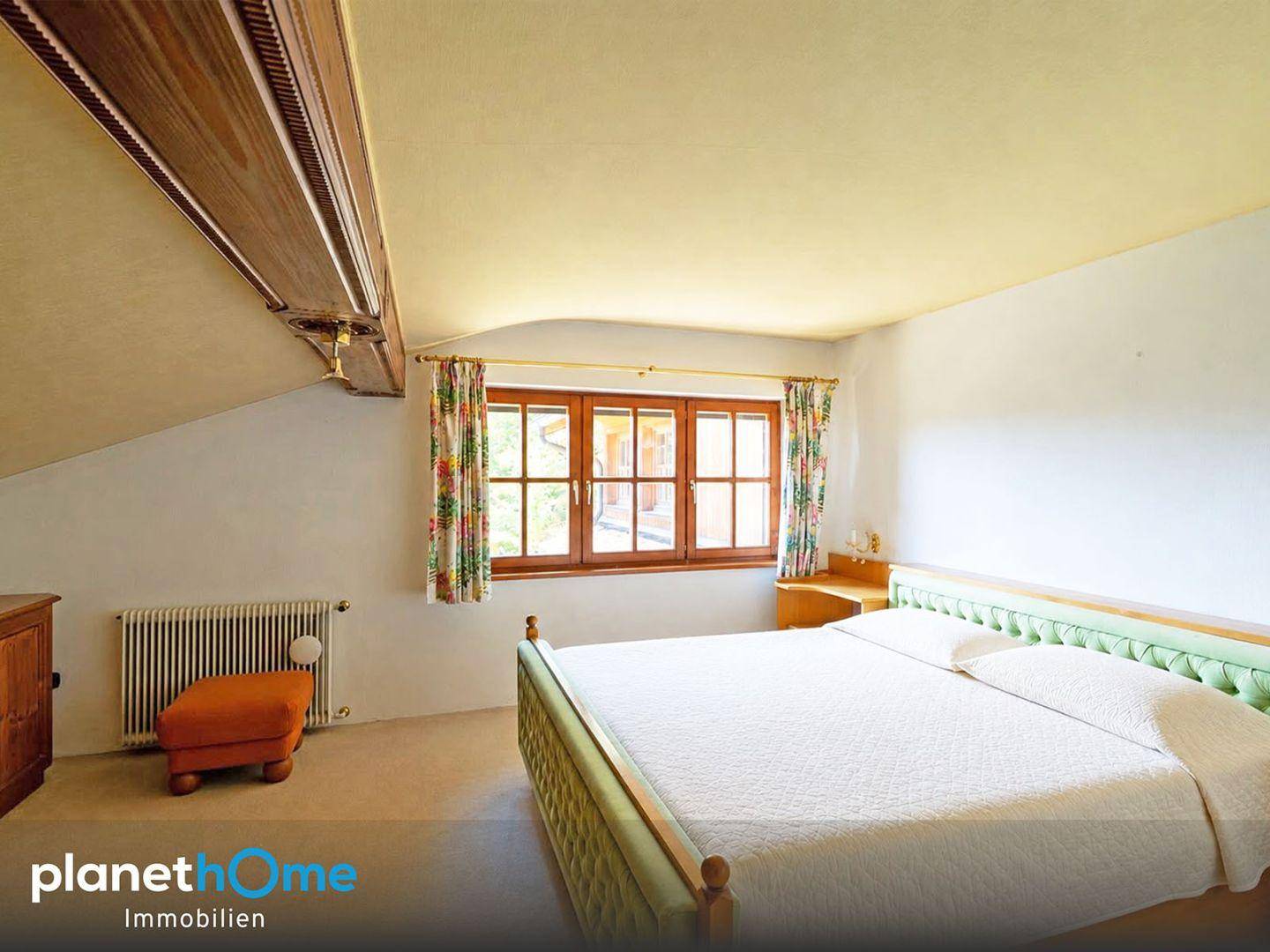 Gemütliches Schlafzimmer mit Doppelbett, Fenster und Dachschräge, hell und einladend gestaltet.