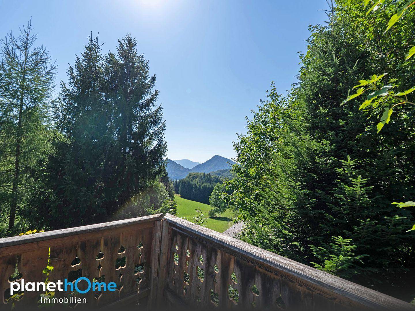 Holzbalkon mit malerischem Ausblick auf die umliegenden Berge und Wälder, perfekt zum Entspannen.
